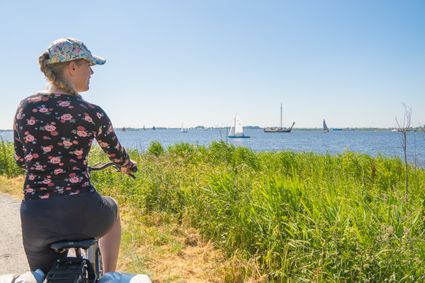 Mirre Oost fietsend langs het water met boten.