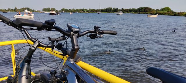 Foto van een fiets op een veerpont met uitzicht op een meer.