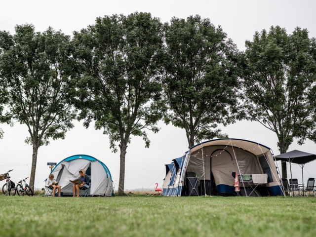 Mensen zittend voor hun tenten op de camping Hoeve Bouwlust in Delft