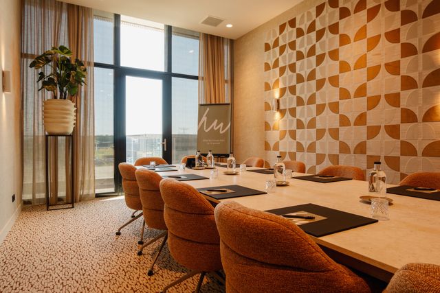 Vergaderlocatie Van der Valk Hotel Woerden in Woerden, provincie Utrecht, moderne vergaderzaal met lange tafel, comfortabele stoelen, presentatiemappen en grote ramen met uitzicht op het Groene Hart.