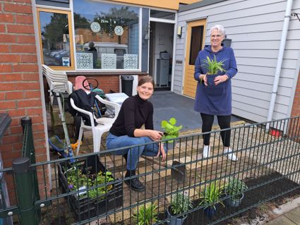Twee personen in een voortuin met planten in de handen