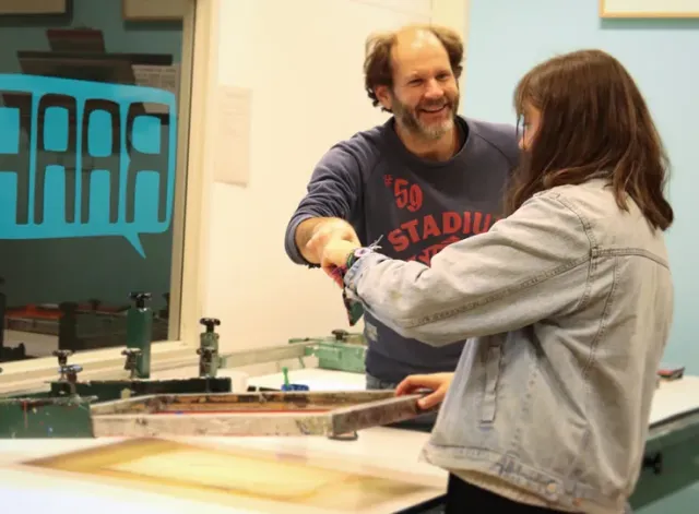 Raaf vrijwilliger Dennis en deelnemer van de zeefdruk cursus in de zeefdruk werkplaats.