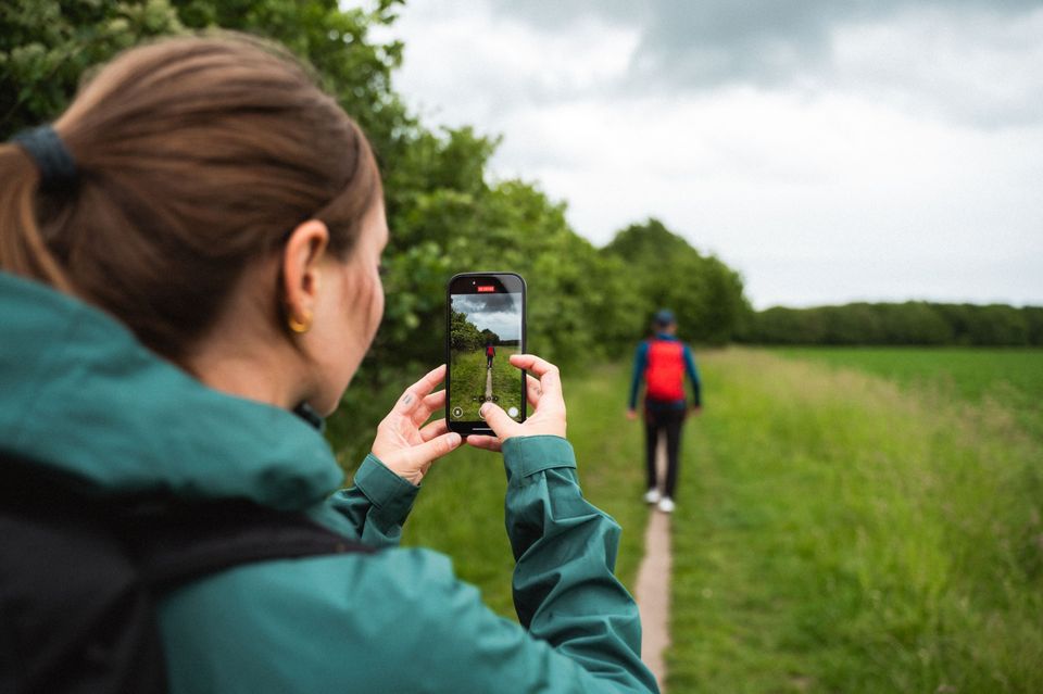Vrouw maakt met mobiel foto van wandelende man