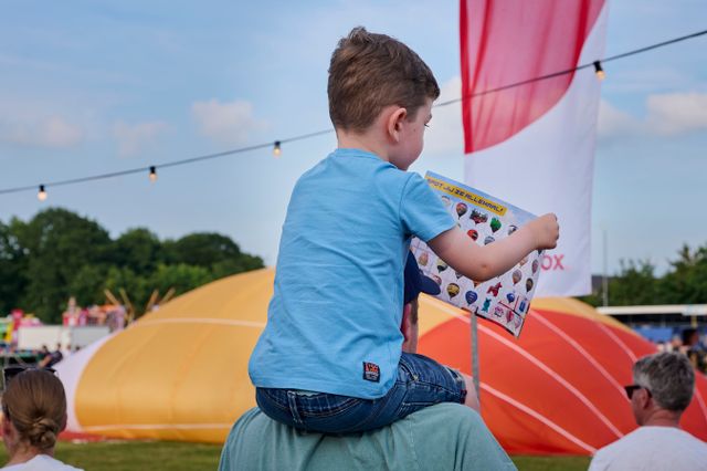 Een jongetje zit op de schouders van zijn vader met een kaart waarop alle ballonnen van de ballon feesten van Joure staan