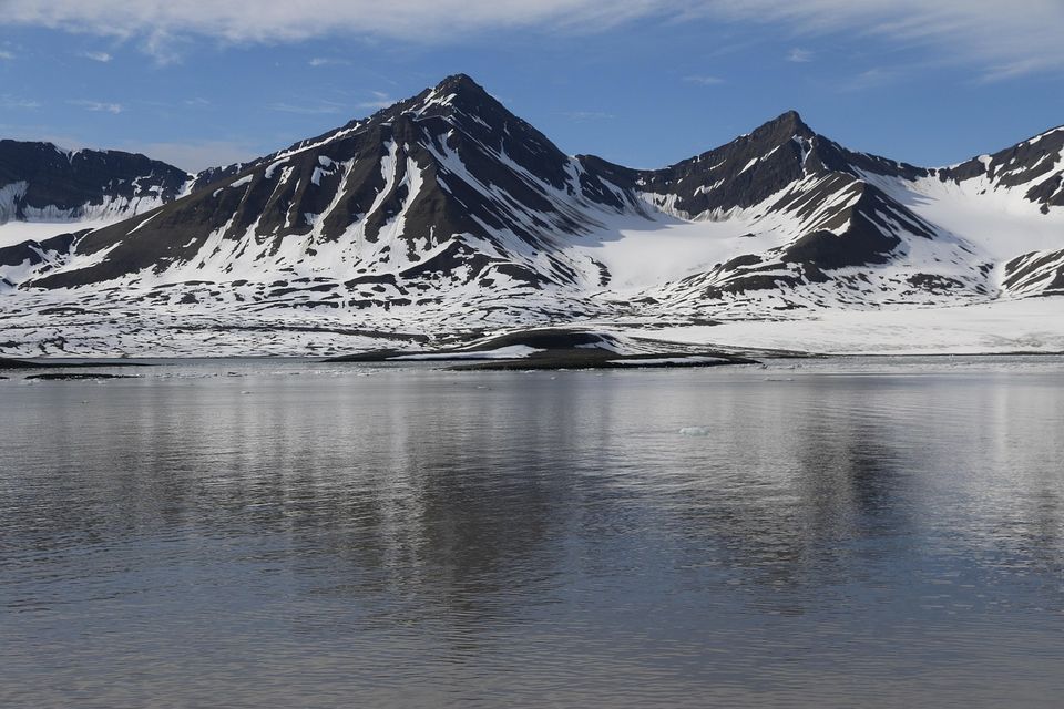 Spitsbergen afgebeeld met besneeuwde bergen aan het water.