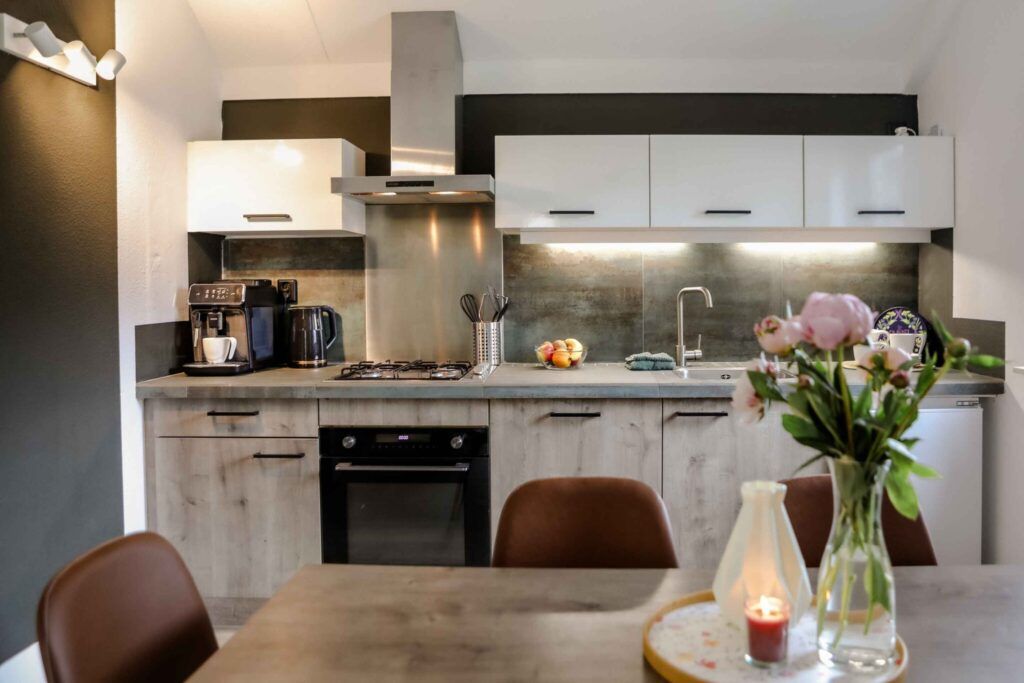 Compleet ingerichte keuken en gezellige eethoek met combi-oven, kookplaat en koffiezetapparaat.
