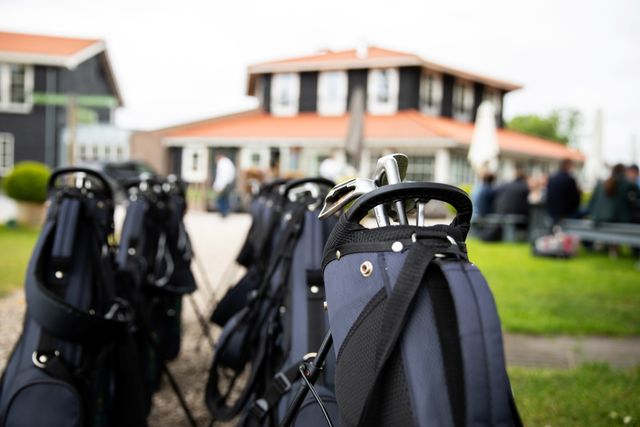 Rij met golfbags en clubs op het terrein van Buitenplaats Kameryck tijdens een golfclinic, met het gebouw op de achtergrond