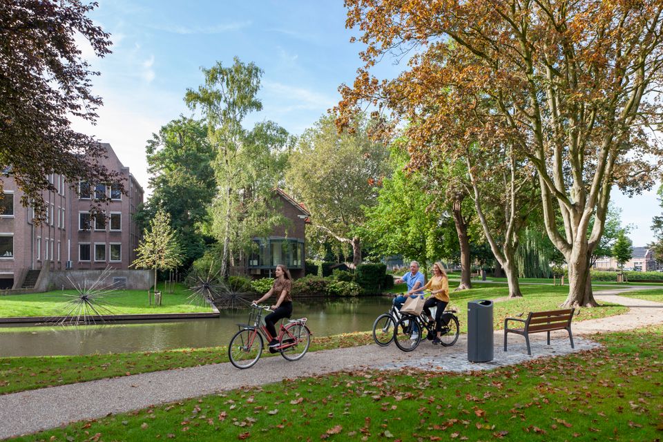Stadspark Westdampark in Woerden, Groene Hart, met fietsers langs het water tussen groene bomen en herfstbladeren.