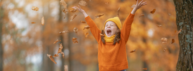 Kind speelt in de herfstbladeren buiten