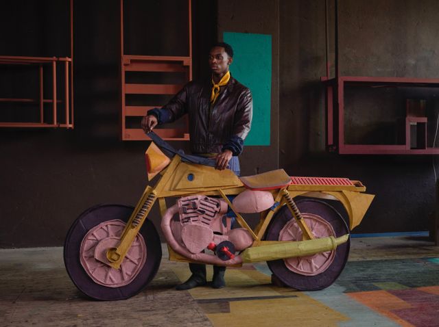 Man staat in lederen jack achter roze motor