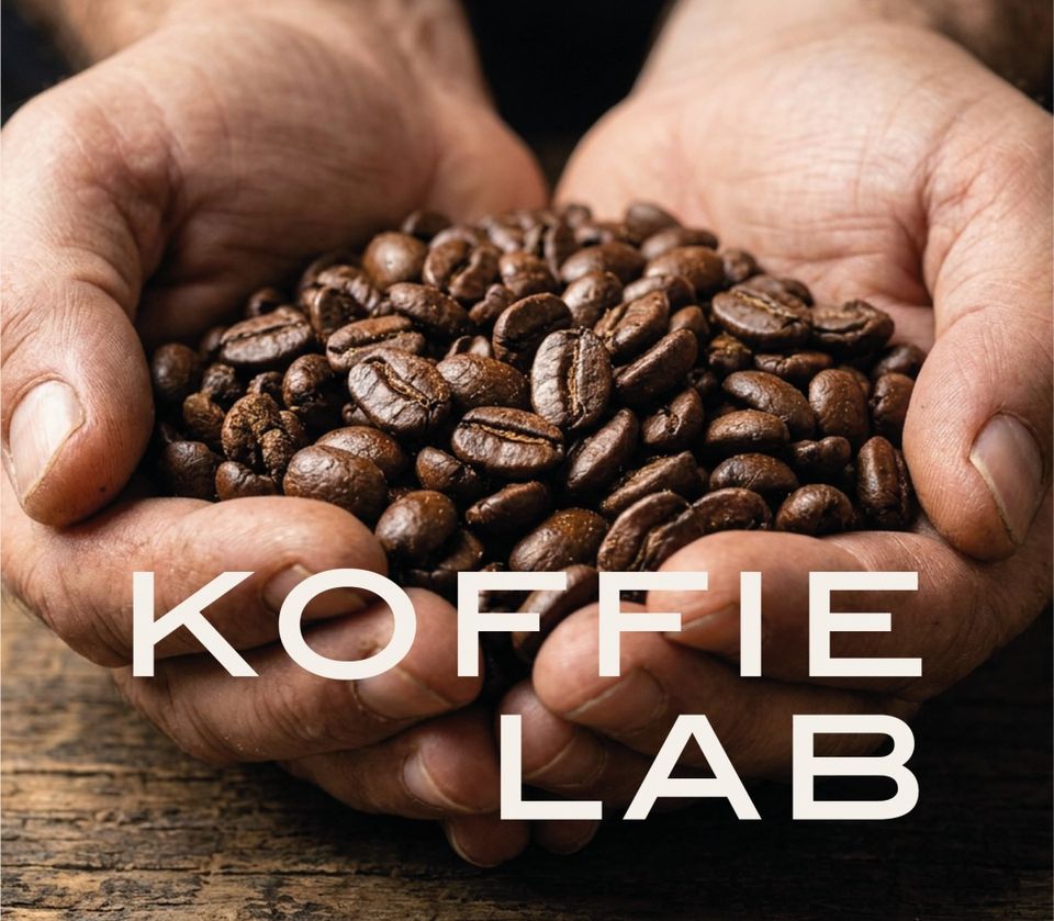 Workshoplocatie Koffie Lab De Hall in Woerden, Groene Hart, met geroosterde koffiebonen in twee handen en het opschrift ‘Koffie Lab’, passend bij een koffie workshop en groepsactiviteit.