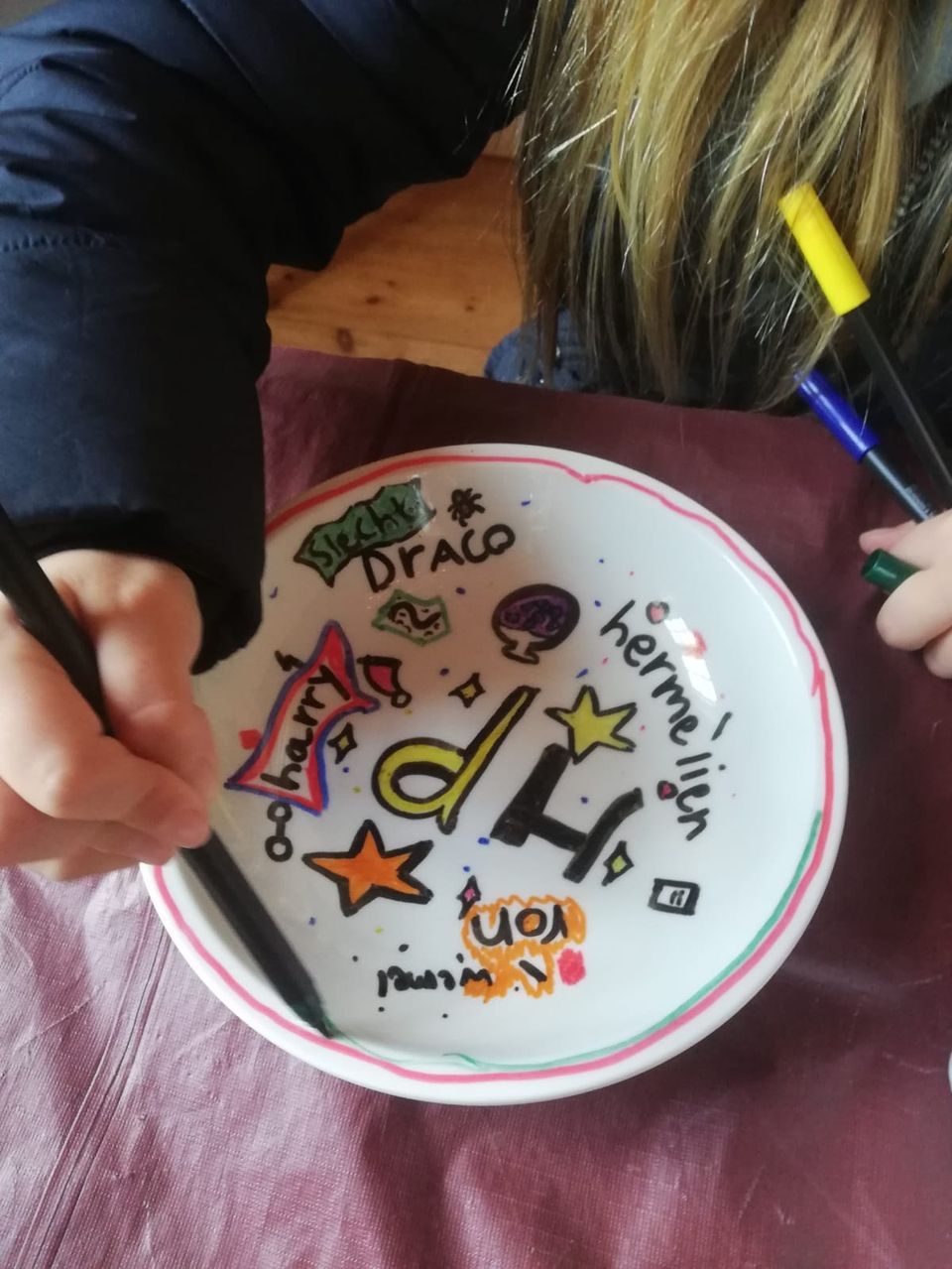 Kind schildert porseleinen bord tijdens workshop