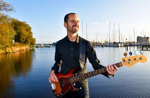 Een foto van man met een gitaar aan het water