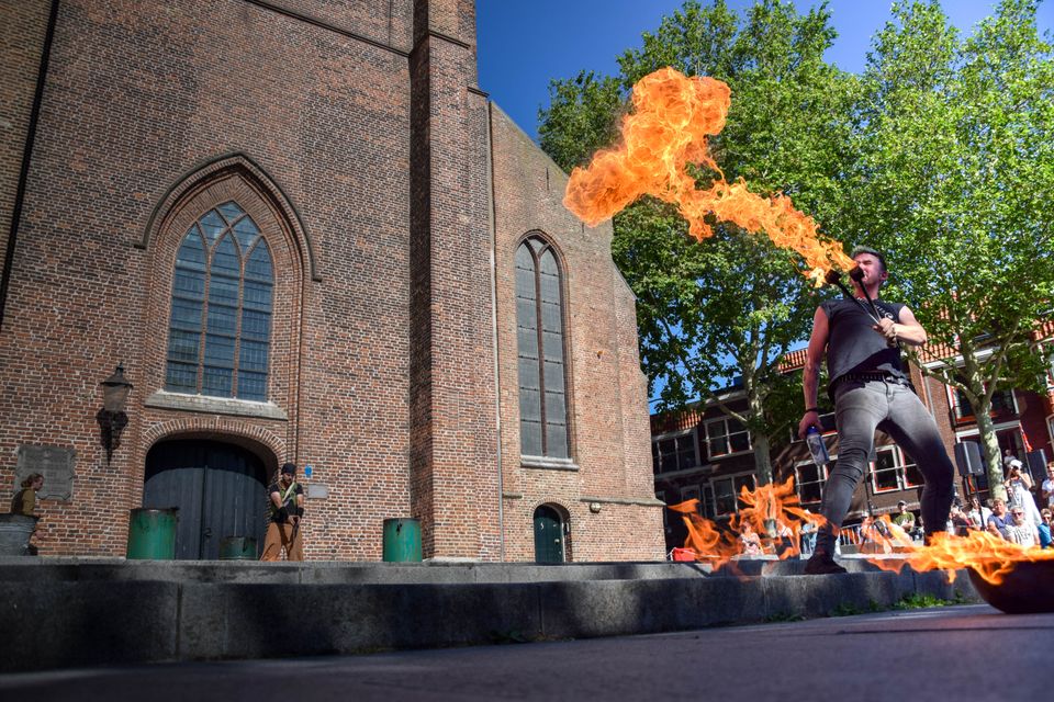 Evenement straatfestival Woerden, provincie Utrecht, Groene Hart, artiest die vuur spuwt op het plein bij een bakstenen kerk met publiek tijdens een zomers festival in het centrum.