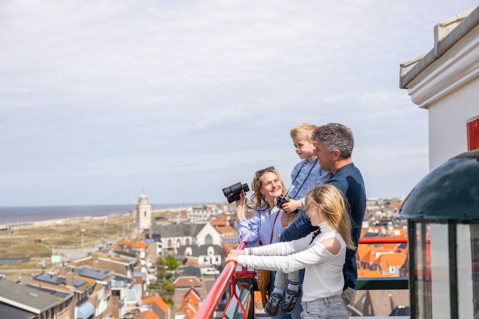 Een gezin kijkt met een verrekijker naar zee, vanaf de vuurtoren in Katwijk aan Zee.