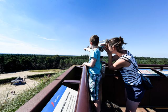 Een moeder en kind bekijken het uitzicht over de bossen vanaf de Pyramide van Austerlitz in Woudenberg. Met een verrekijker kijken zij uit over de Utrechtse Heuvelrug.