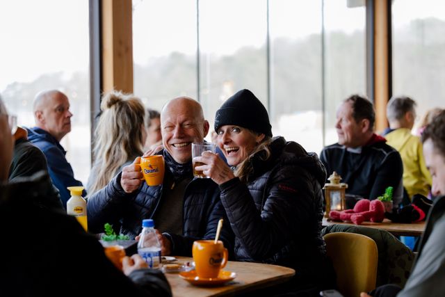 Man en vrouw lachend met een mok chocolademelk in een restaurant