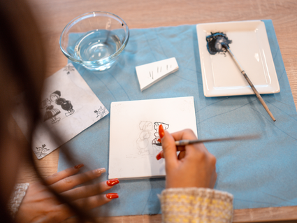Dame tekent een Delfts Blauw tegeltje bij een tegelworkshop in het Royal Delft museum