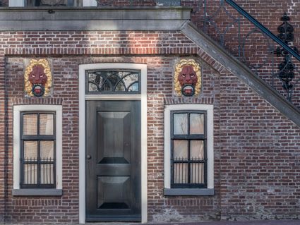 twee leeuwenkoppen op een gevel in balk.