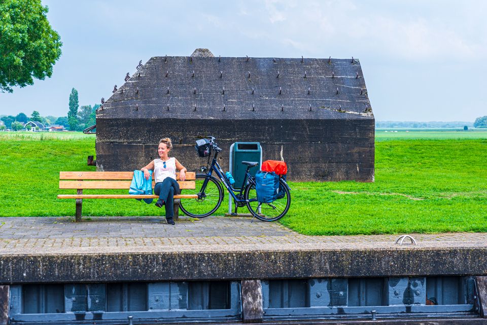 Fietser rust uit op bankje voor bunker Hollandse Waterlinies