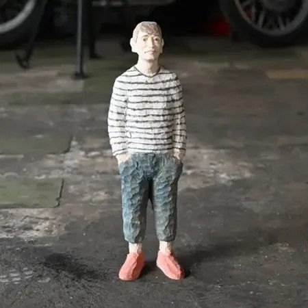 Man in hout in een blauwe broek, wit met blauw gestreepte trui en rode schoenen.