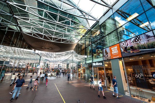 Binnen in het overdekte gedeelte van het stadshart met veel mensen en veel winkels.