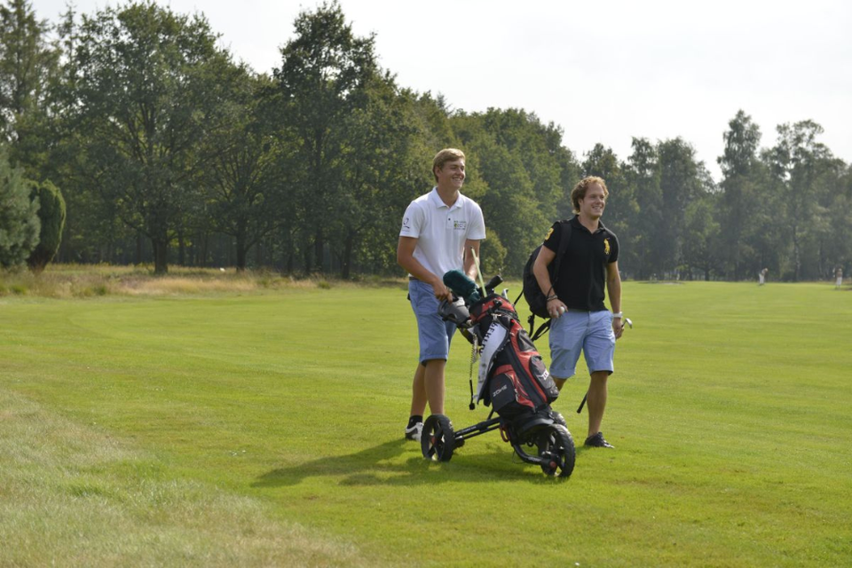Twee heren lopen op de golfbaan.