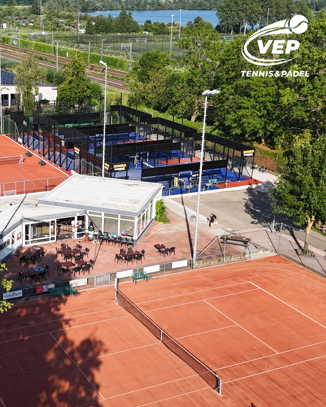 Tennis- en padelpark VEP Tennis & Padel, met graveltennisbanen, blauwe padelbanen, clubhuis en terras in een groene omgeving aan het water.