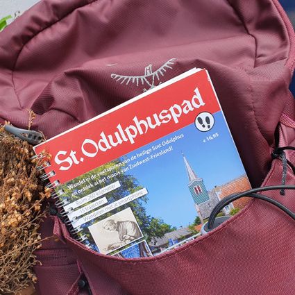 Boekje van St. Odulphuspad steekt uit rugzak