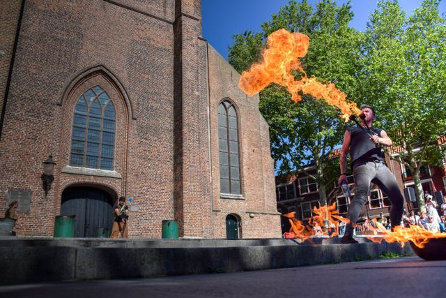 Evenement straatfestival Woerden, provincie Utrecht, Groene Hart, artiest die vuur spuwt op het plein bij een bakstenen kerk met publiek tijdens een zomers festival in het centrum.