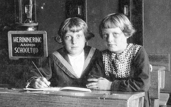 oude foto van twee kinderen achter een schrijftafel