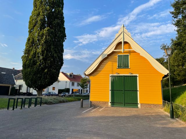 Een geel, houten gebouw met groene gesloten deuren in een ouderwetse stijl.