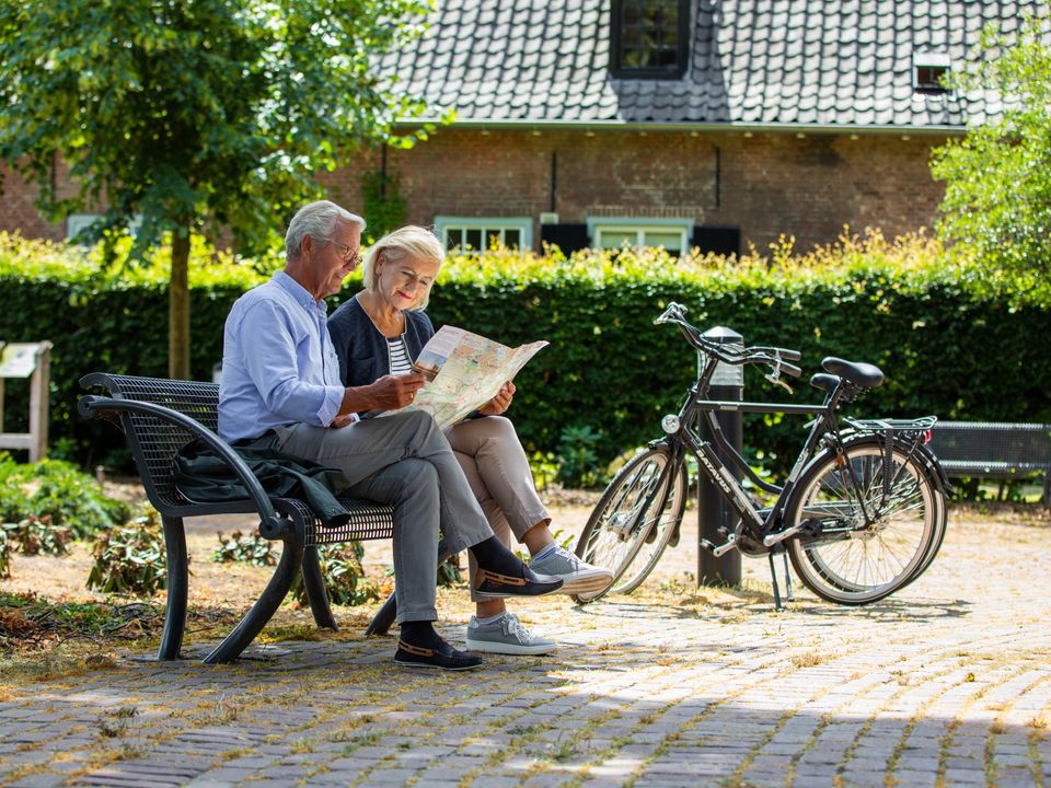 Twee fietsers die op een bankje naar de routekaart kijken