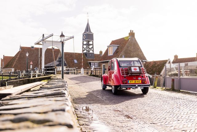 Rode eend auto rijdt over een brug in Zuidwest Friesland.