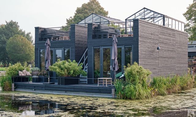 Een aanzicht van een greenhouse vanaf het water.