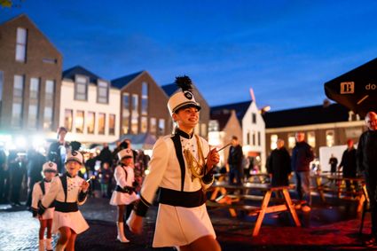 Kinderen in witte uniformen lopen tijdens een feestelijke optocht door de binnenstad van Woerden, als onderdeel van de Koetjes en Kalfjes Parade.