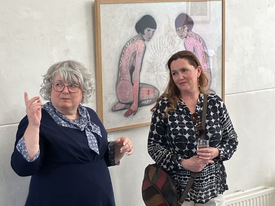 Kunstgalerie Galerie Van Slagmaat in Woerden, Groene Hart, twee vrouwen tijdens een expositie met een figuratief kunstwerk aan de wand.