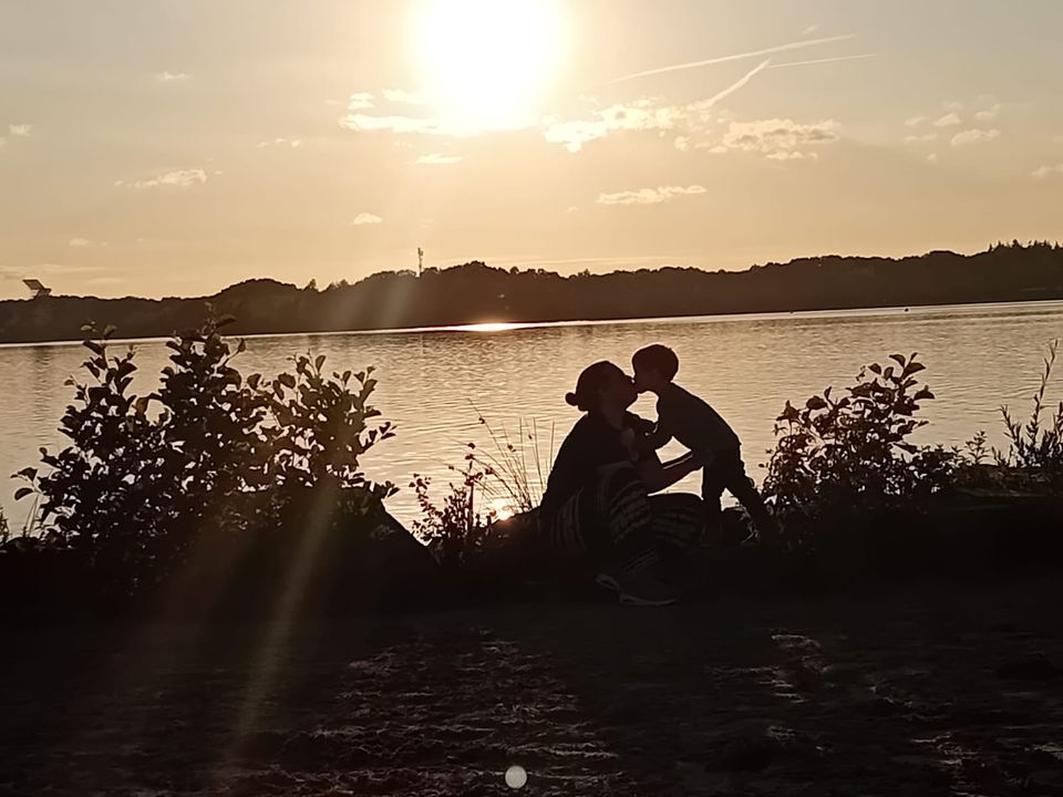 Zoon geeft moeder kusje bij meer met zonsondergang