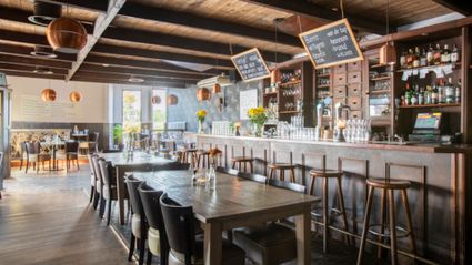 Sfeervol interieur van restaurant Fabels Eten en Drinken in Woerden met houten tafels, bar en koperen lampen.