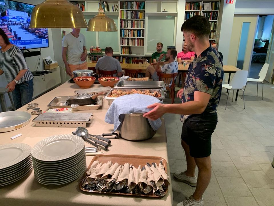 Een man staat voor een tafel vol met borden en heerlijk eten.