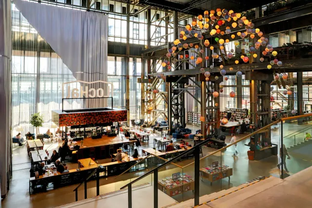 Indrukwekkend sfeerbeeld van het hoge gebouw van de LocHal met grote glazen raampartij en een mooi kunstwerk met bollen