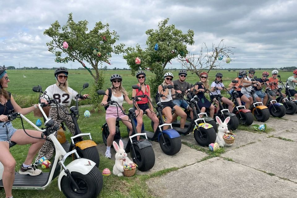 Recreatieve scoutertour van Scouter Tour Het Groene Hart in Hekendorp, Oudewater, Groene Hart. Groep deelnemers op scouters tijdens een buitenactiviteit door het polderlandschap, met paasversiering en uitgestrekte weilanden op de achtergrond.
