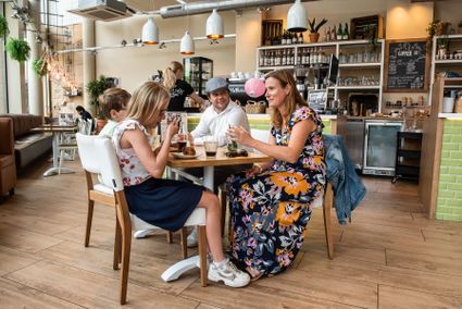 Mensen zitten in een restaurant te eten en drinken en te kletsen met elkaar.