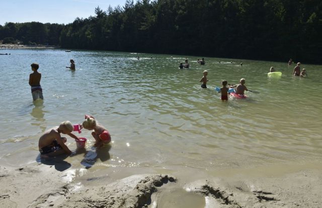 Kinderen spelen in het water met emmertjes.
