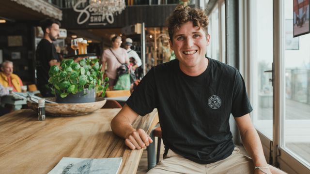 tim zit aan de houten tafel bij beachclub Natural High