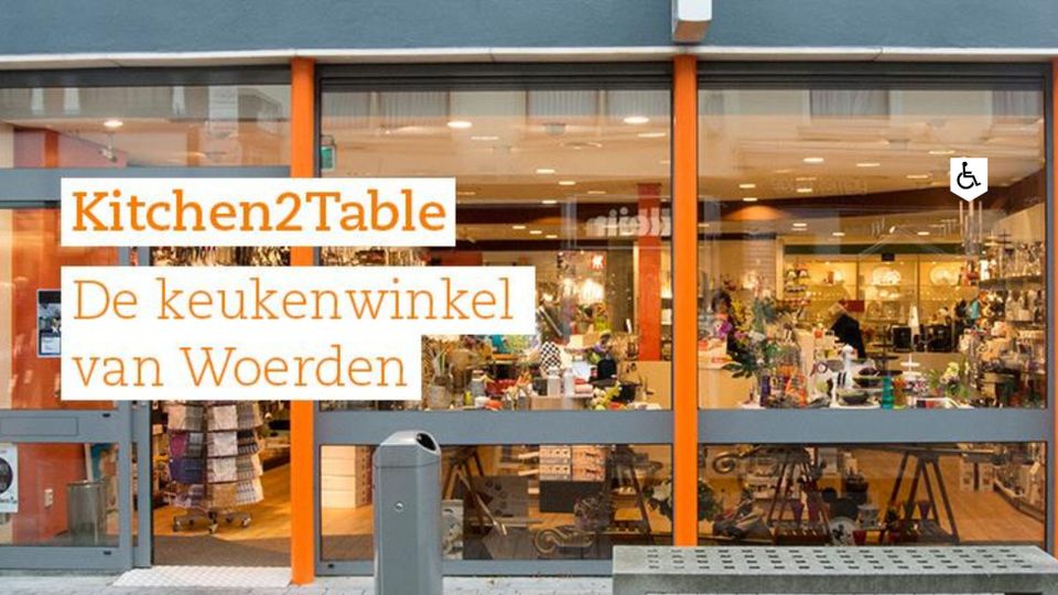 Speciaalzaak Kitchen2Table Woerden, provincie Utrecht, Groene Hart, glazen pui met zicht op kookgerei, servies en keukenaccessoires in de keukenwinkel in het centrum.