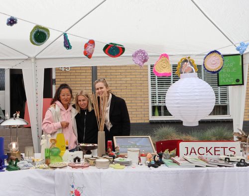 Mensen die achter een marktkraam staan met spullen