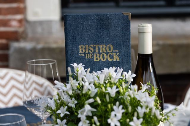 Foto van een gedekte tafel bij Bistro de Bock in Woerden, met een menu en een fles wijn