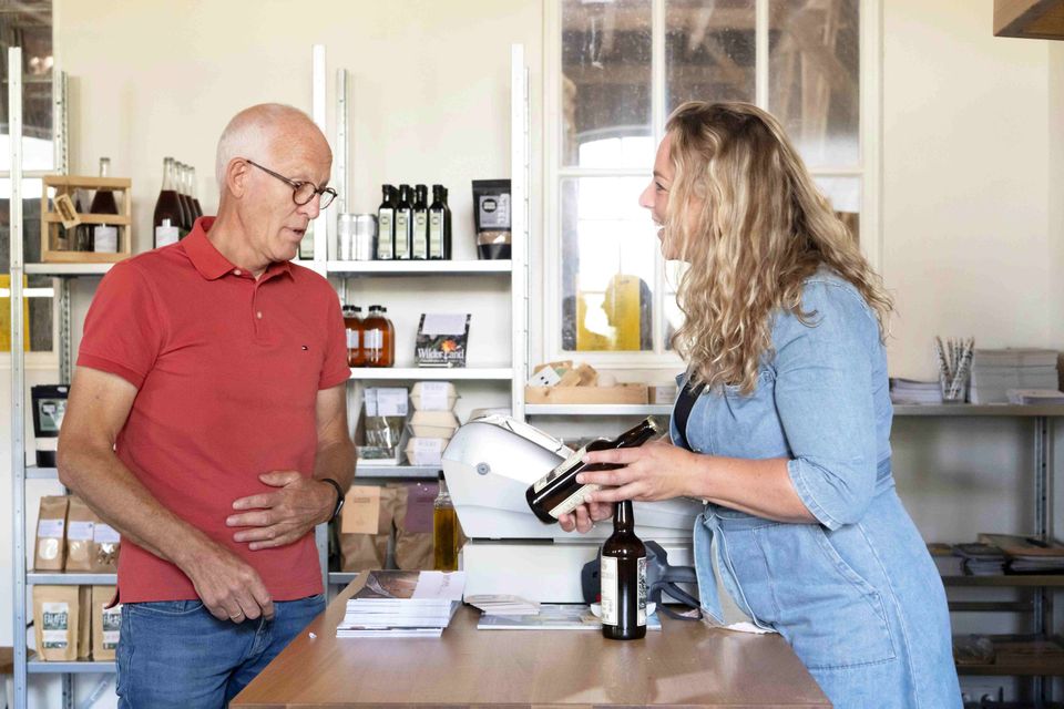Hoeve Koning Willem 3 in Zuidwest-Drenthe, vrouw laat streekproduct zien aan man.