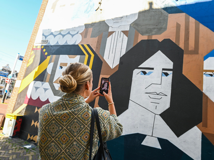 Dame maakt een foto van het kunstwerk in de Kloksteeg van Delft